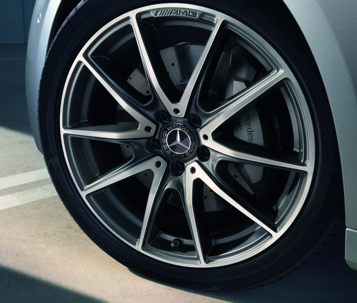 Auschnitt eines Rads an einem Silbernen Fahrzeug. Die Felge ist silbern mit einem AMG-Logo am Rand und einem Mercedes-Stern in der Mitte. Das Bild verlinkt auf die Kategorie: Felgen.